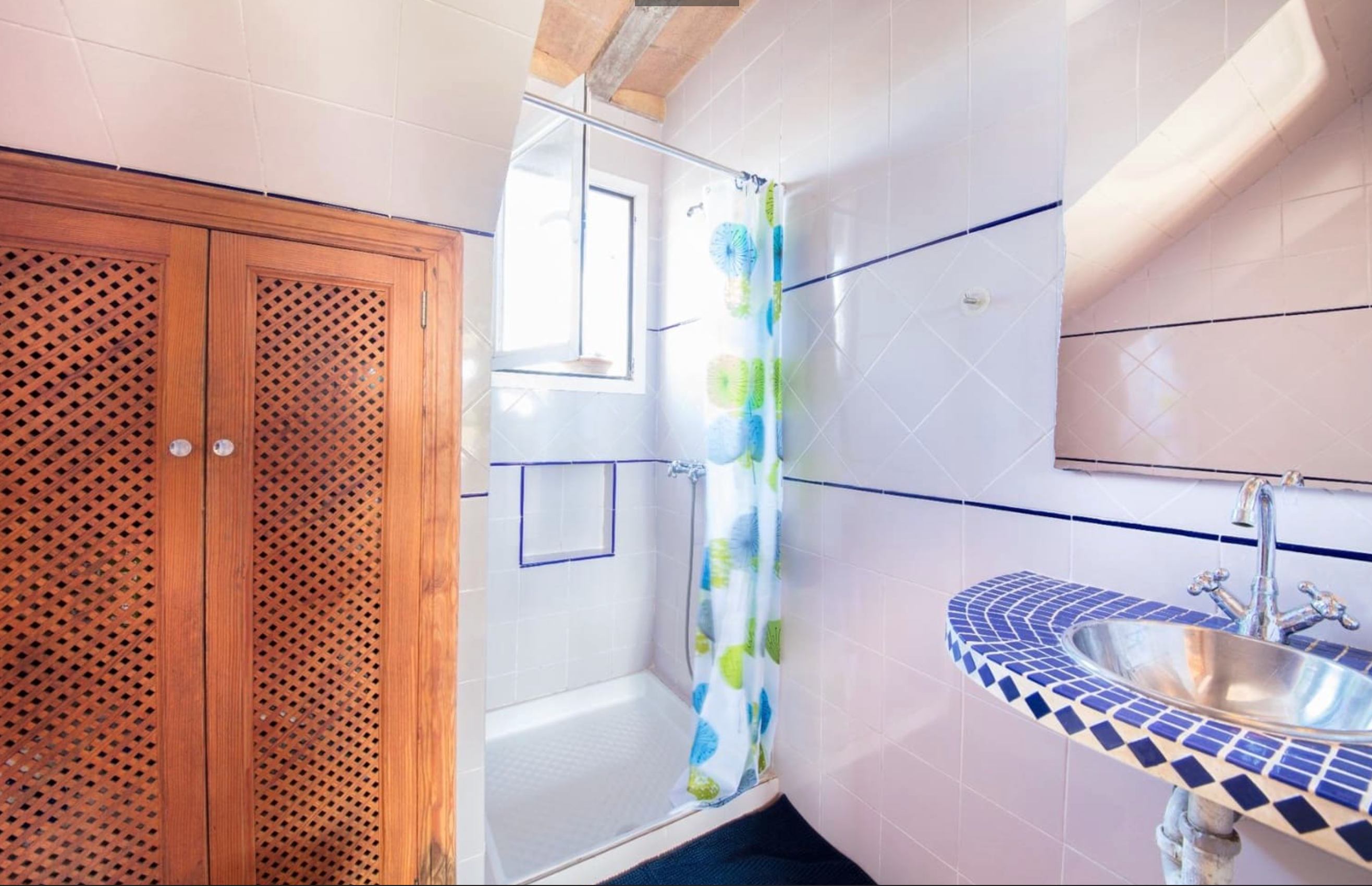 Bathroom with shower, blue mosaic tile countertop and wooden accents
