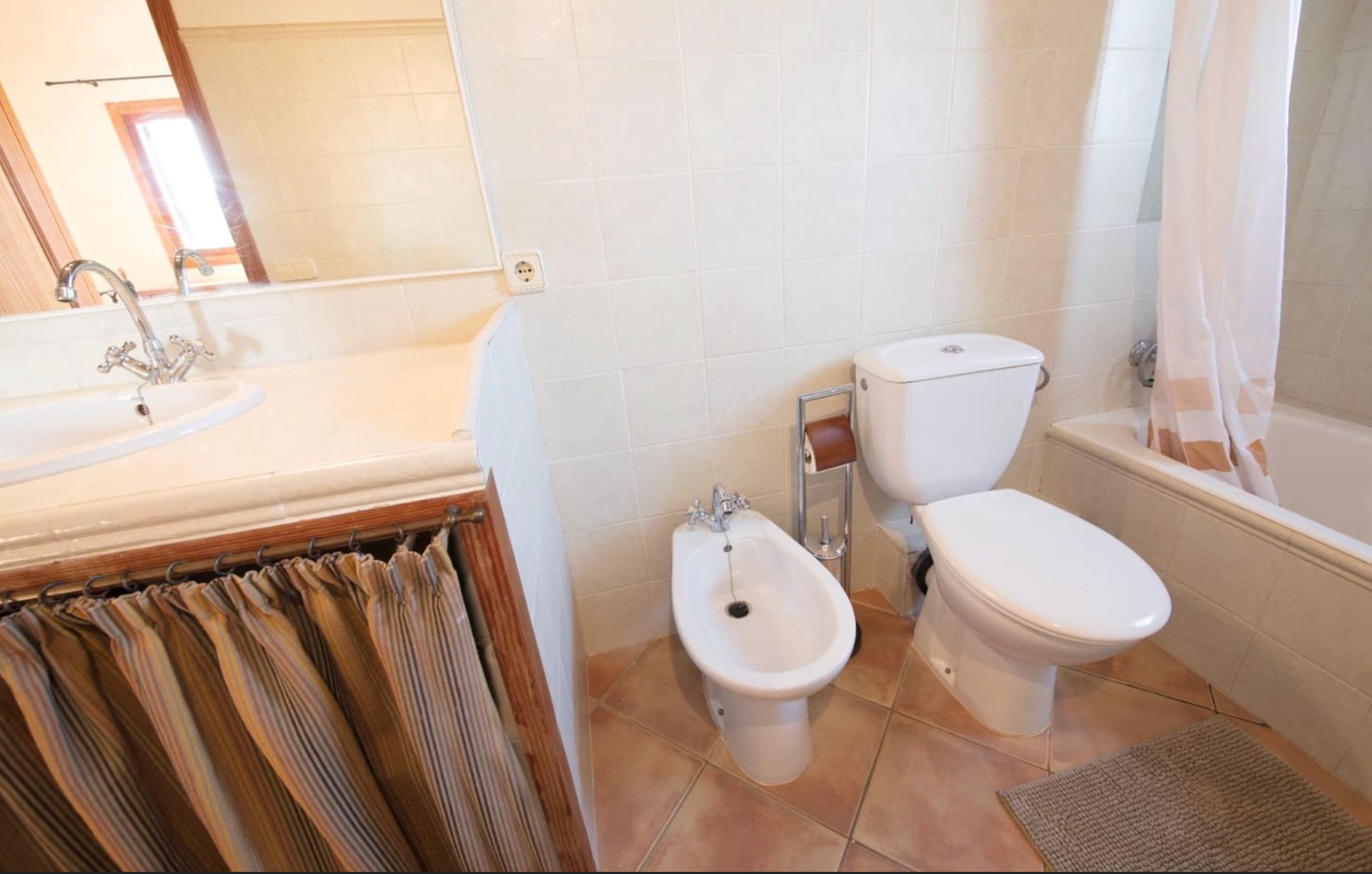 Bathroom with striped curtain sink and bathtub