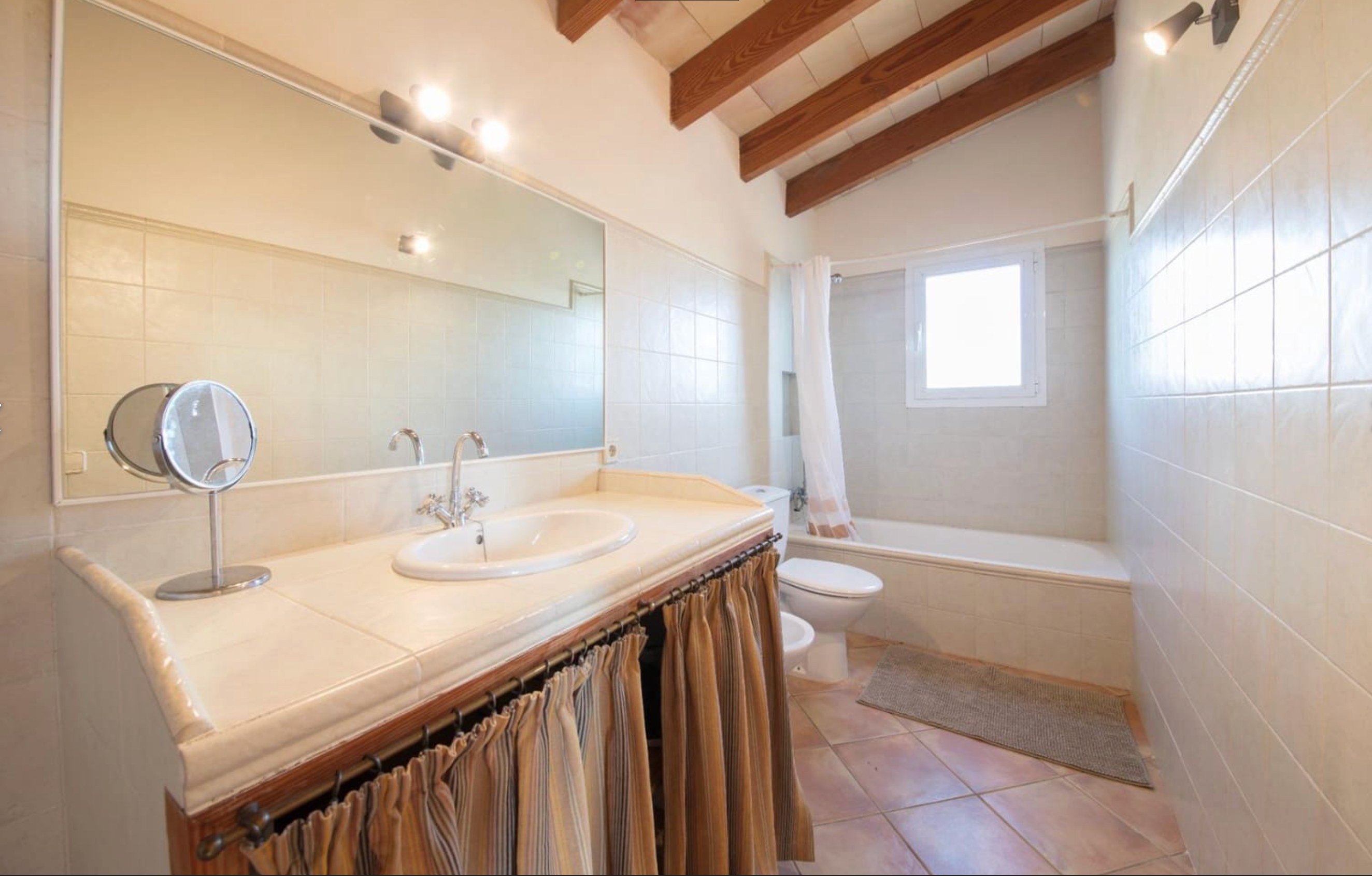 Spacious bathroom with large mirror and exposed beam ceiling