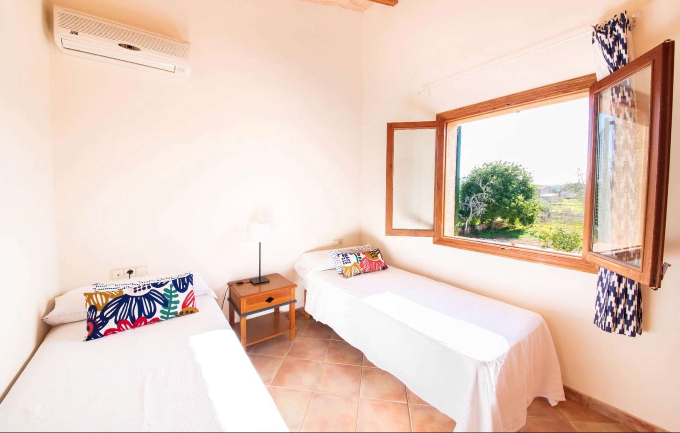 Twin bedroom with colorful pillows and scenic countryside view