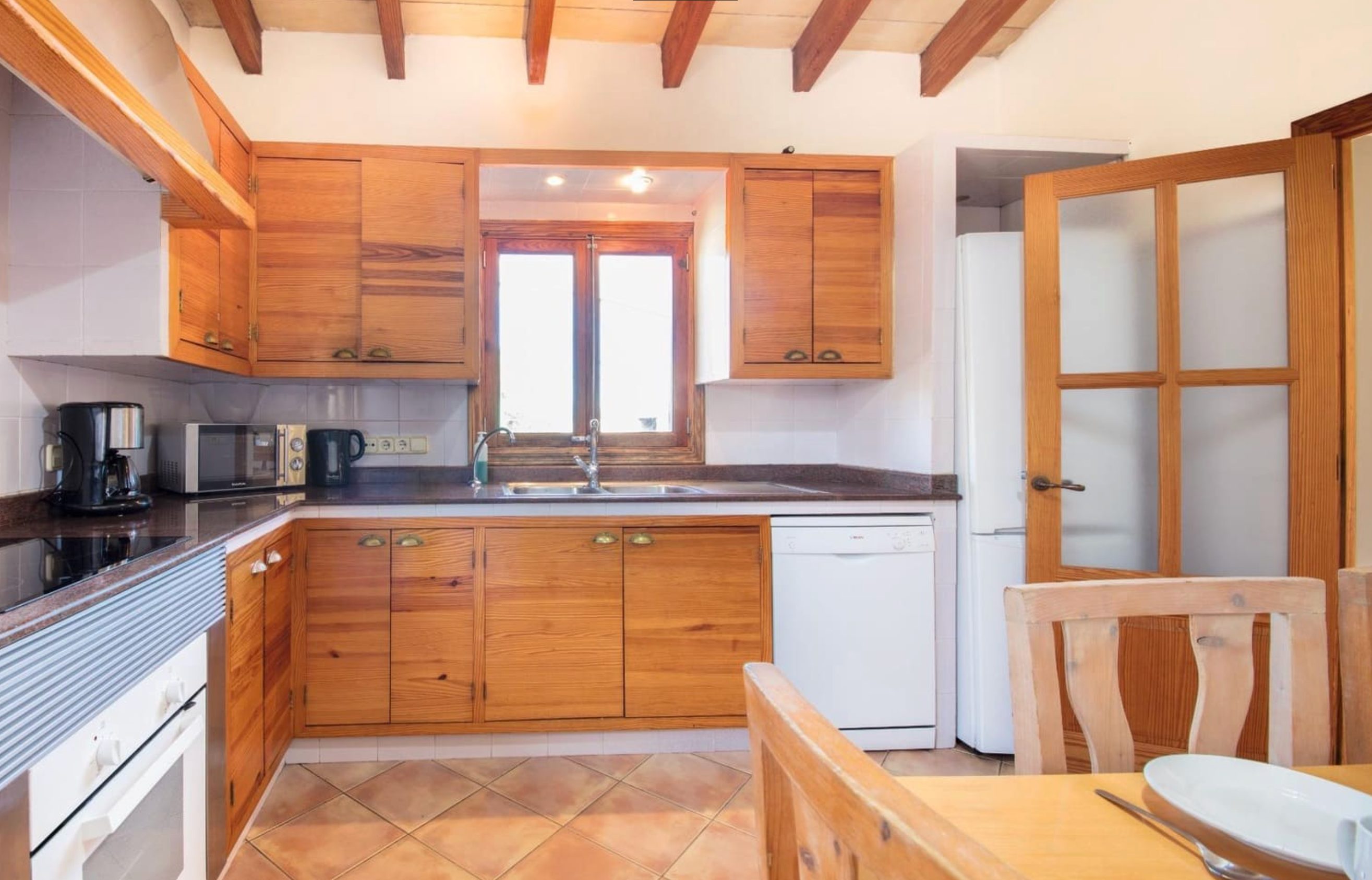 Fully equipped kitchen with wooden cabinetry and terracotta floors